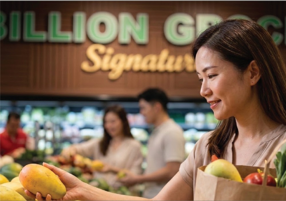 Shopper picking fresh produce inside the Billion Grocer anchor tenant